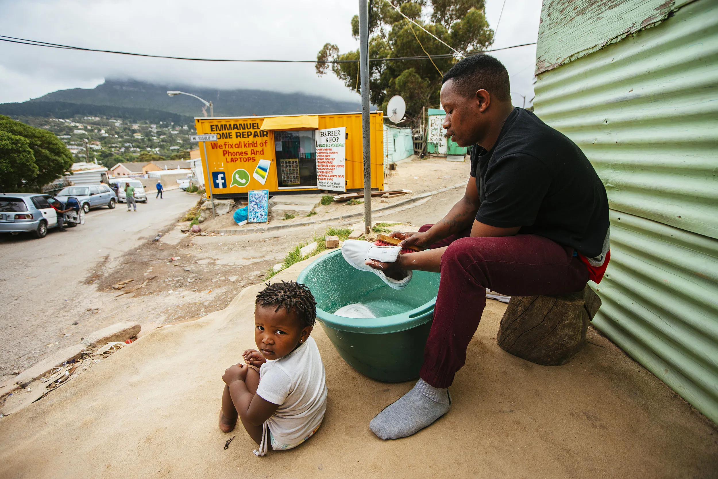 A resident washes a pair of shoes in a bucket of water in the Imizamo Yethu township outside Cape Town, South Africa.