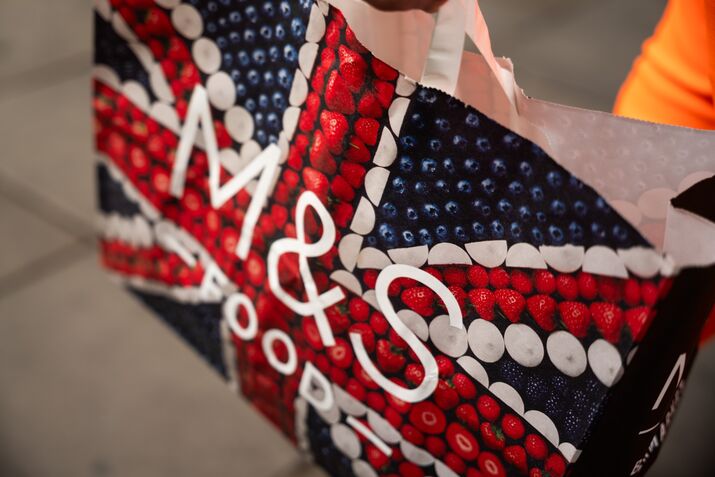 A customer carries an M&S-branded paper bag