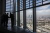 Visitors take in the city skyline view from the 15th floor pantry area inside the European Central Bank (ECB) headquarters as skyscrapers tower over commercial and residential property in Frankfurt, Germany.