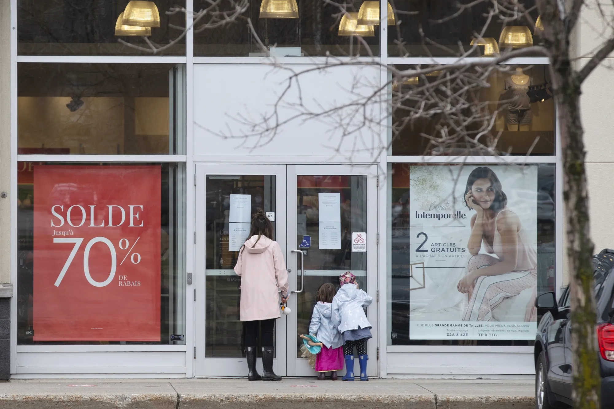People look through the window of a closed store in Quebec City on May 4, 2020.