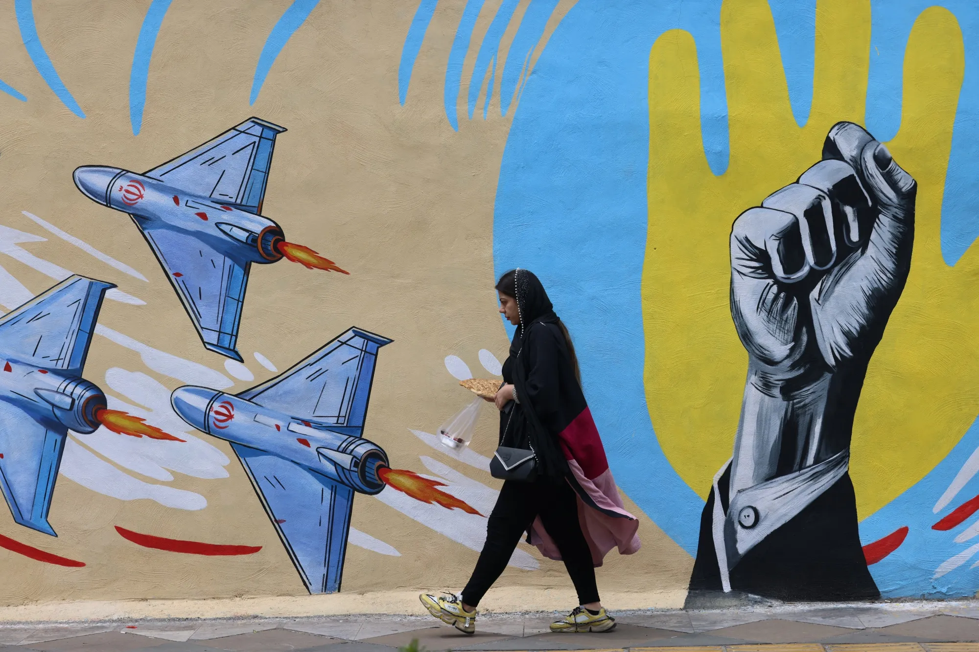 A woman walks past a mural in Tehran on Wednesday.