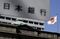 A Japanese national flag flies while signage for the Bank of Japan (BOJ) is displayed outside the central bank's headquarters in Tokyo, Japan, on Tuesday, March 15, 2016. The BOJ refrained from bolstering its record monetary stimulus as policy makers gauge the impact of the negative interest-rate strategy they adopted in January. Photographer: Kiyoshi Ota/Bloomberg