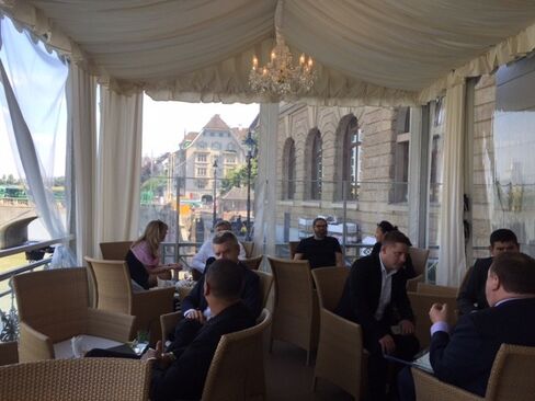 Art Basel power brokers conduct business on the terrace of Les Trois Rois. Photographer: Katya Kazakina