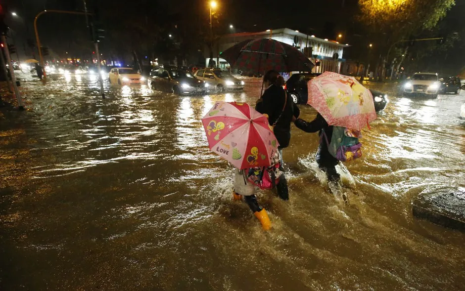 A woman and two children cross a flooded street after the Seveso River overflowed due to heavy rain in Milan in 2014.