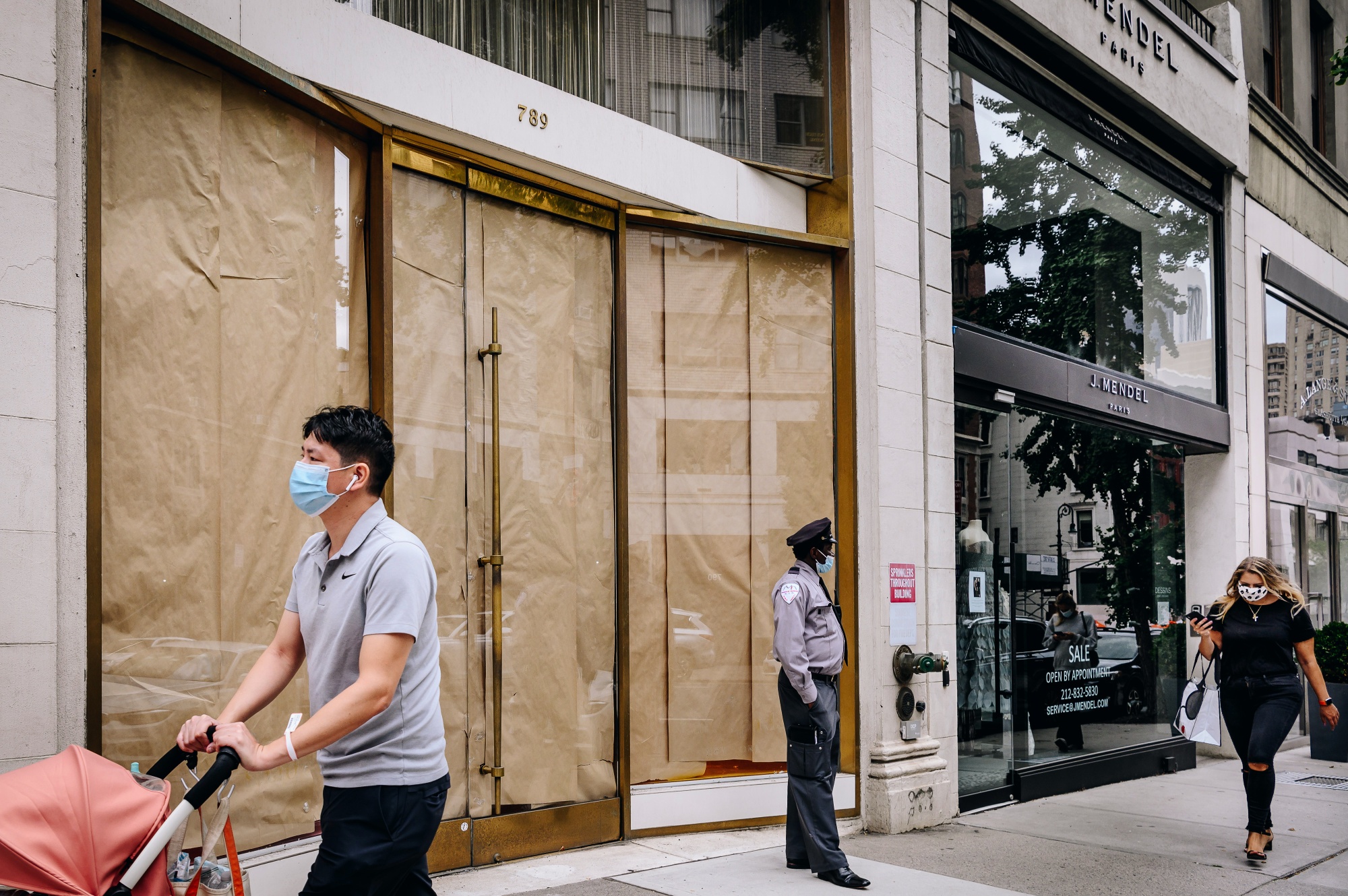 Pedestrians pass by a closed storefront on Madison Avenue.