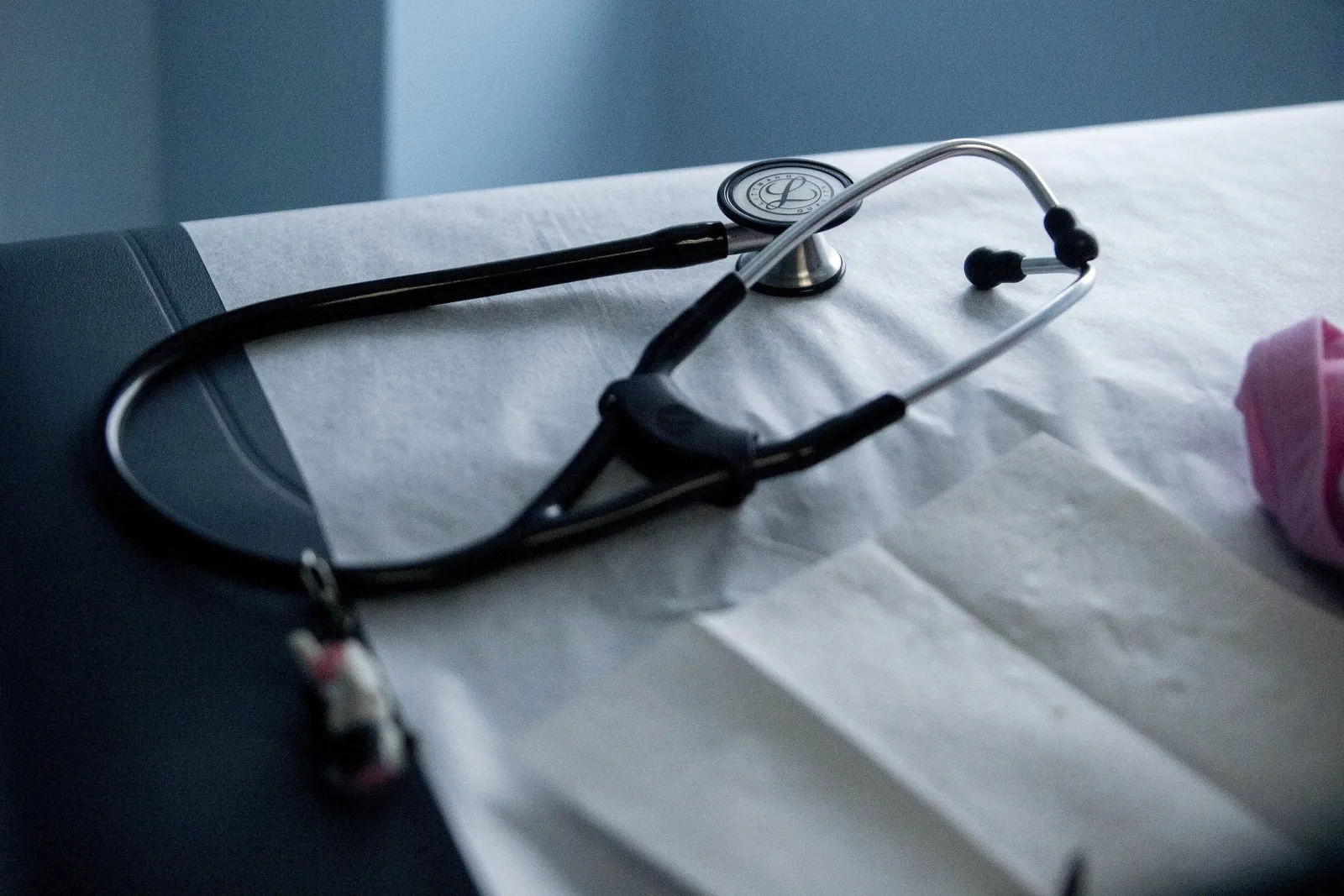A stethoscope sits on an examination table in an exam room.