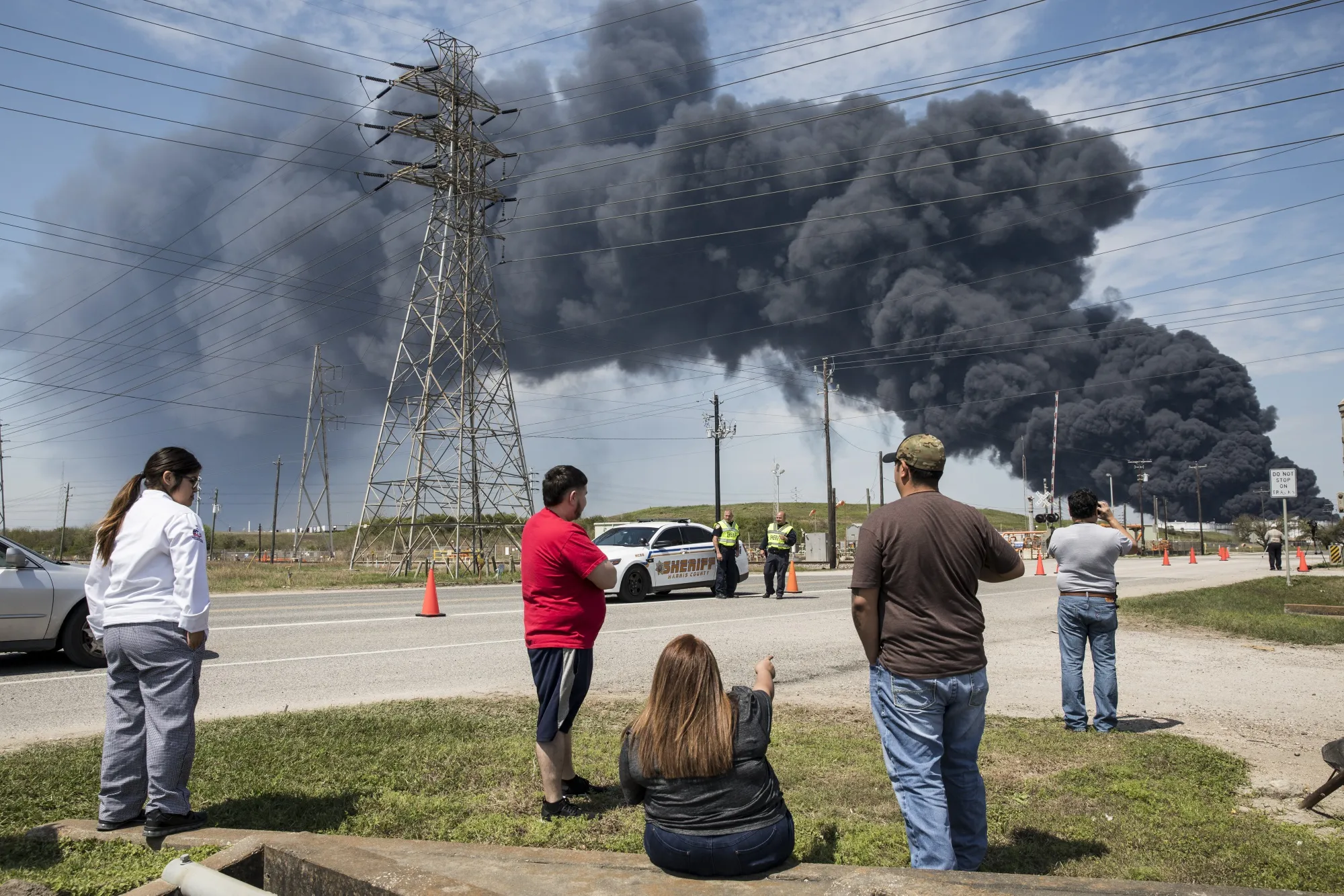 Residents look on at the plume of smoke rising from a fire at the Intercontinental Terminals petrochemical storage site in Deer Park, Texas on March 19.