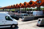 Automobiles queue to pay at toll booths operated by Abertis Infraestructuras SA on a highway in Granollers, Spain, on Thursday, May 27, 2015.