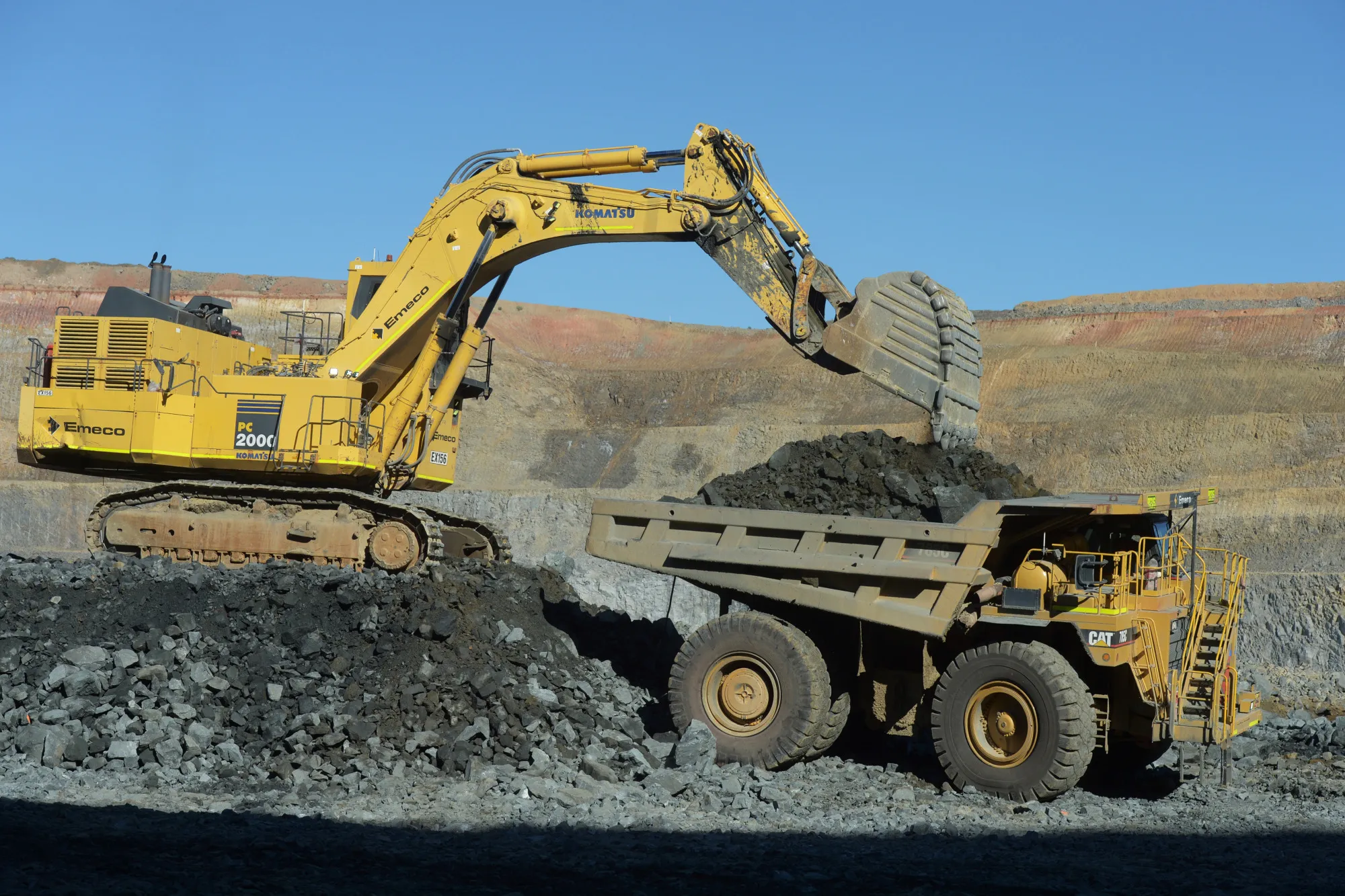 An excavator deposits ore into a dump truck in an open pit&nbsp;gold mine in Mungari, Australia.