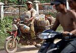 A Cambodian smuggler (L) rides his motorbike in Kandal province loaded with gasoline he got from neighbouring Vietnam, some 40 kms south of Phnom Penh. 
