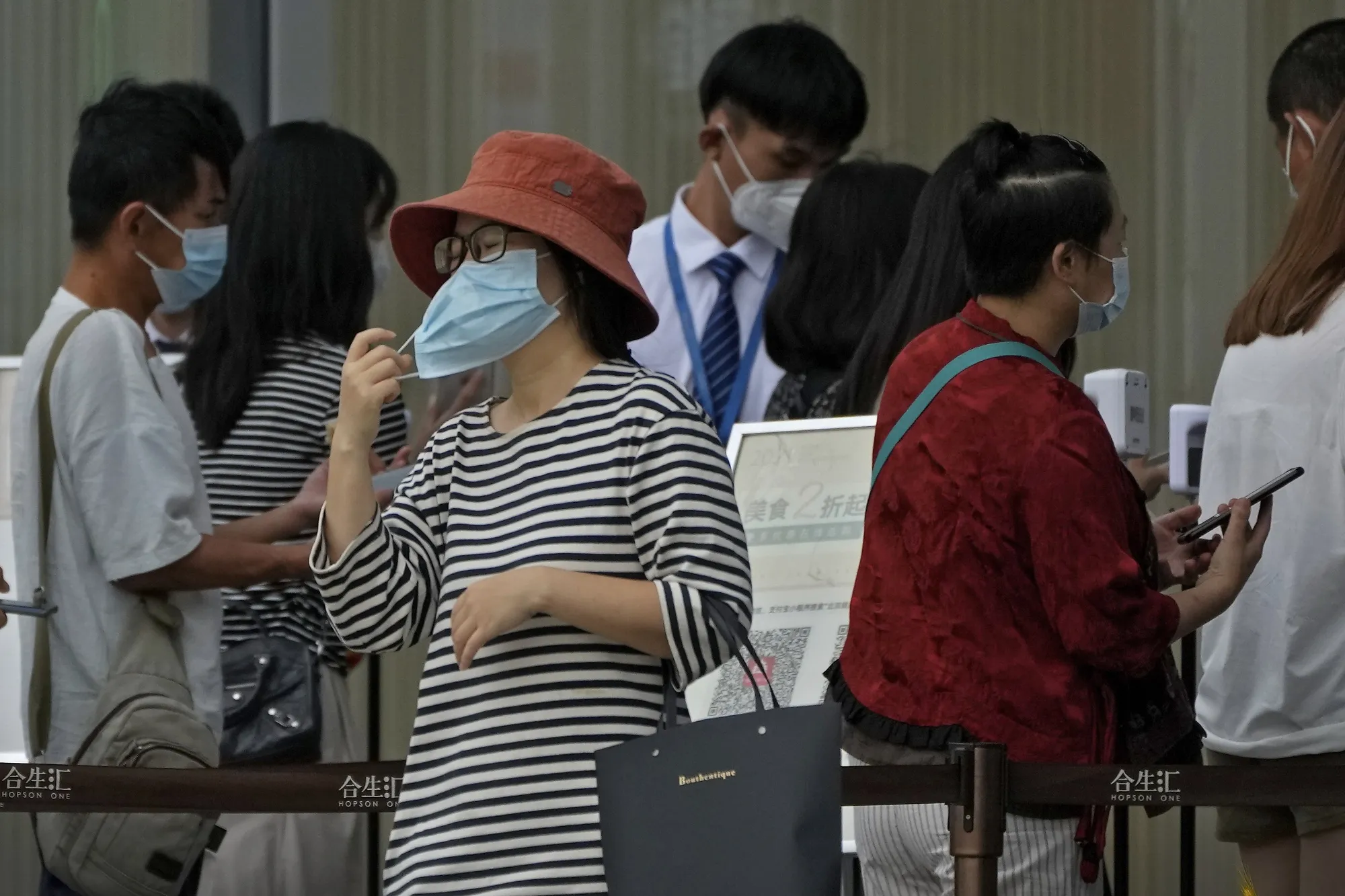 Visitors line up to scan health check QR codes before entering a shopping mall in Beijing, on Aug. 28.