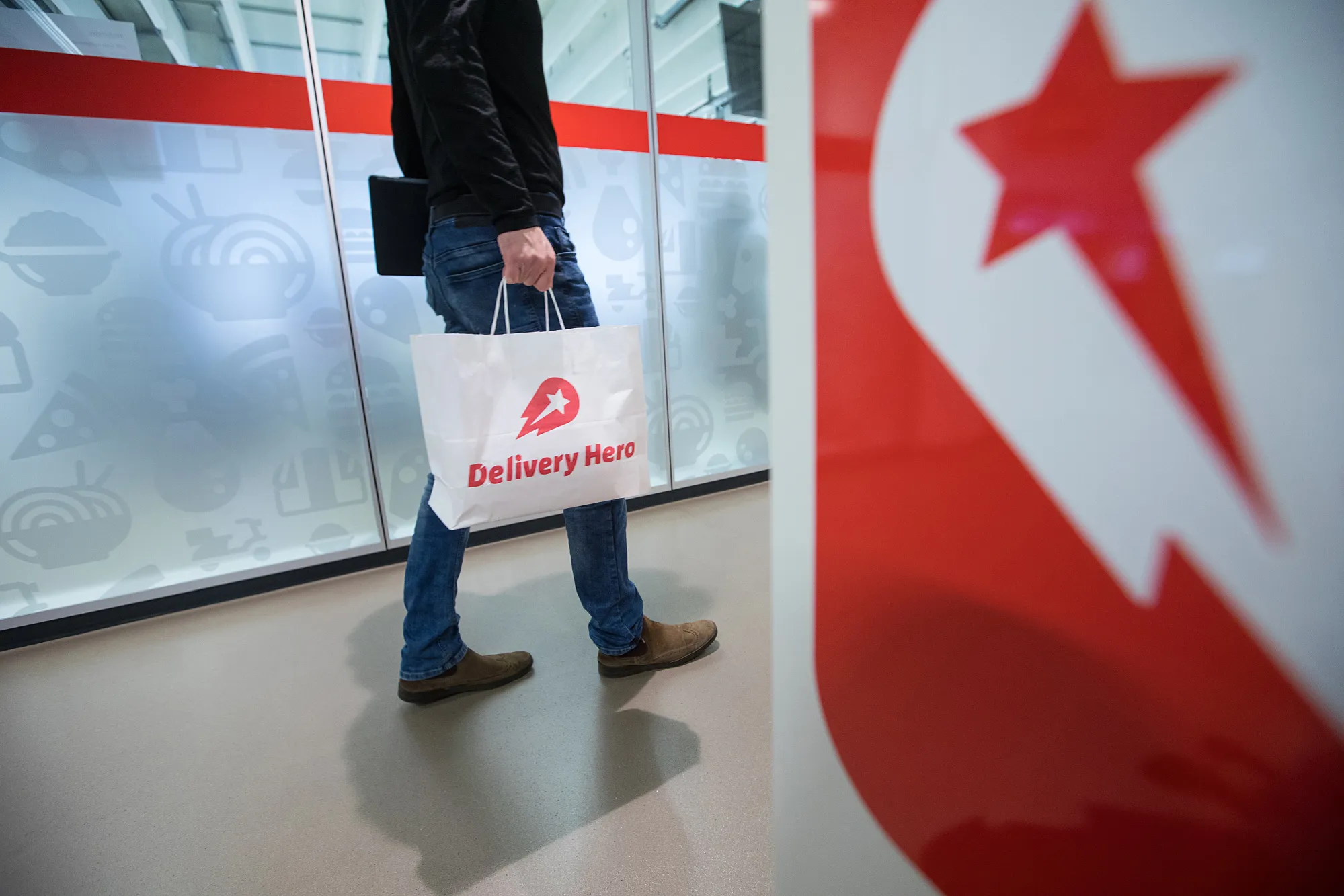 An employee carries a branded paper bag inside the Delivery Hero AG headquarter offices in Berlin, Germany.