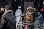 Security personnel check the temperature of people with an advanced thermo camera at a subway station in Beijing on Jan. 27, 2020.