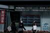 Pedestrians wearing protective masks walk past an electronic stock board outside a securities firm in the Shinjuku district of Tokyo, Japan, on Wednesday, Feb. 17, 2021. A surge in Japanese shares this week has pushed the Nikkei 225 past the 30,000 level for the first time since 1990.