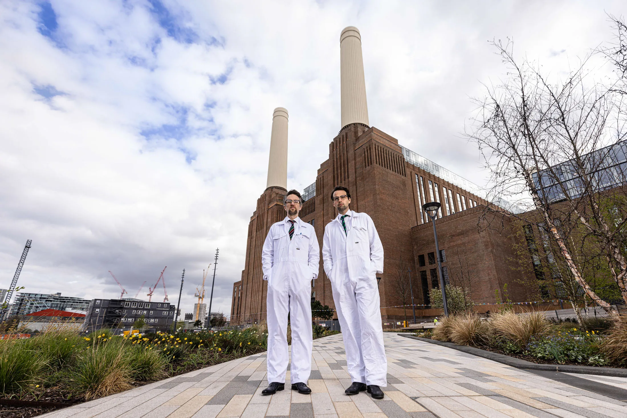 Boiler-suit clad bartenders from Control Room B stand in front of the revitalized Battersea power station in London.&nbsp;