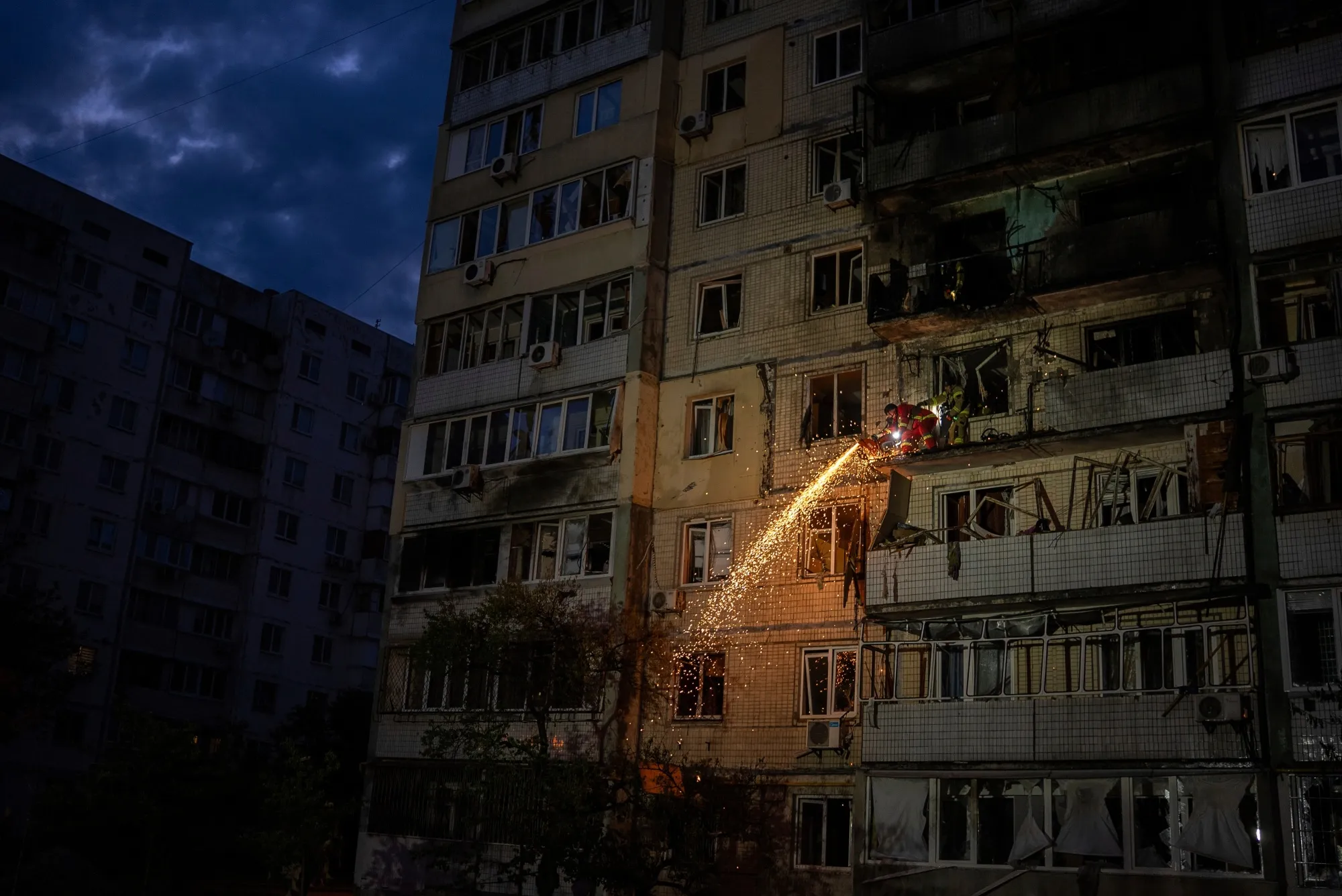 Firefighter clear debris from a balcony at a residential building damaged after a Russian attack in Kyiv on May 24.