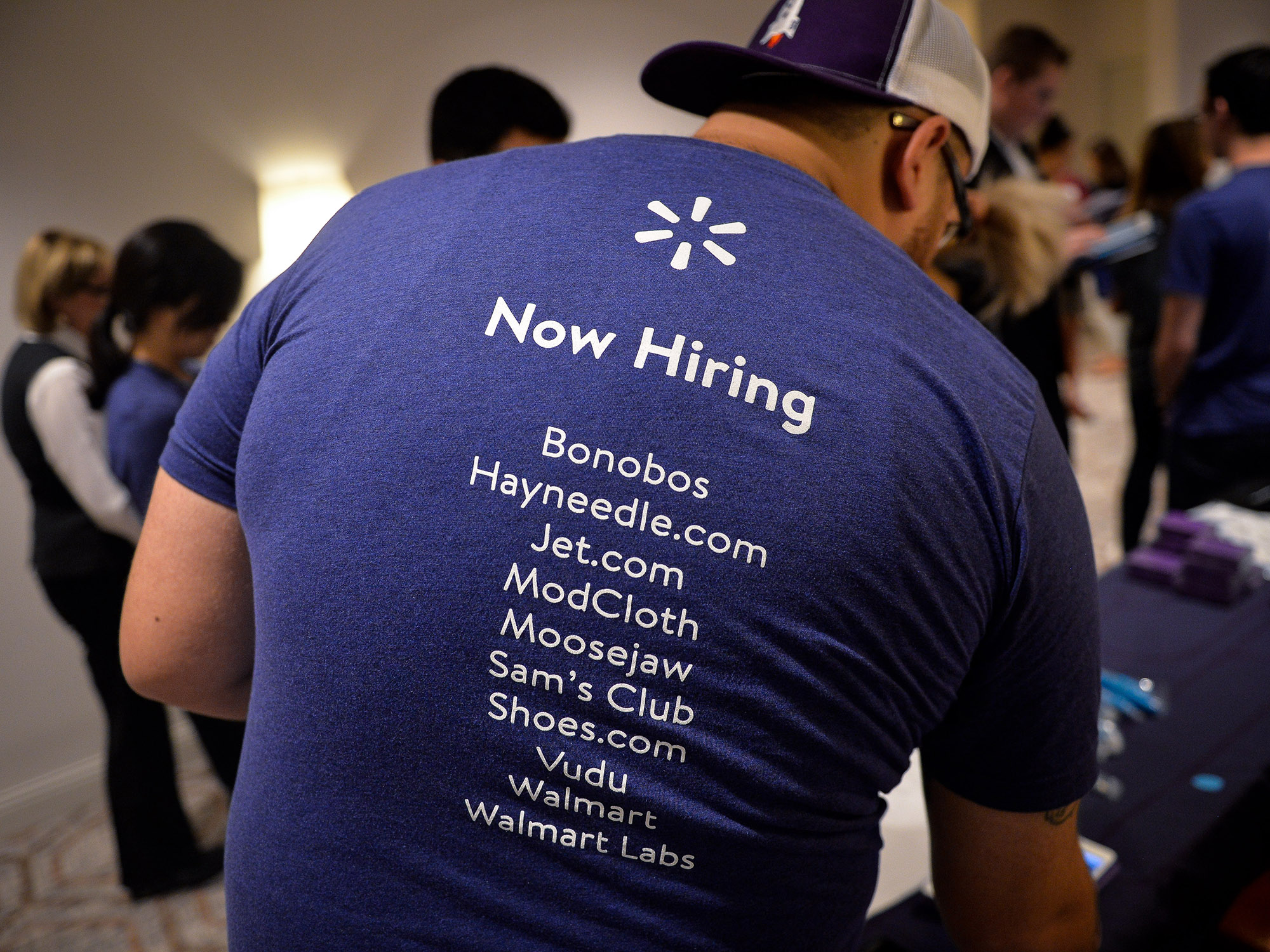 A job recruiter wears a shirt showing all of the Walmart brands during a career fair in Philadelphia.