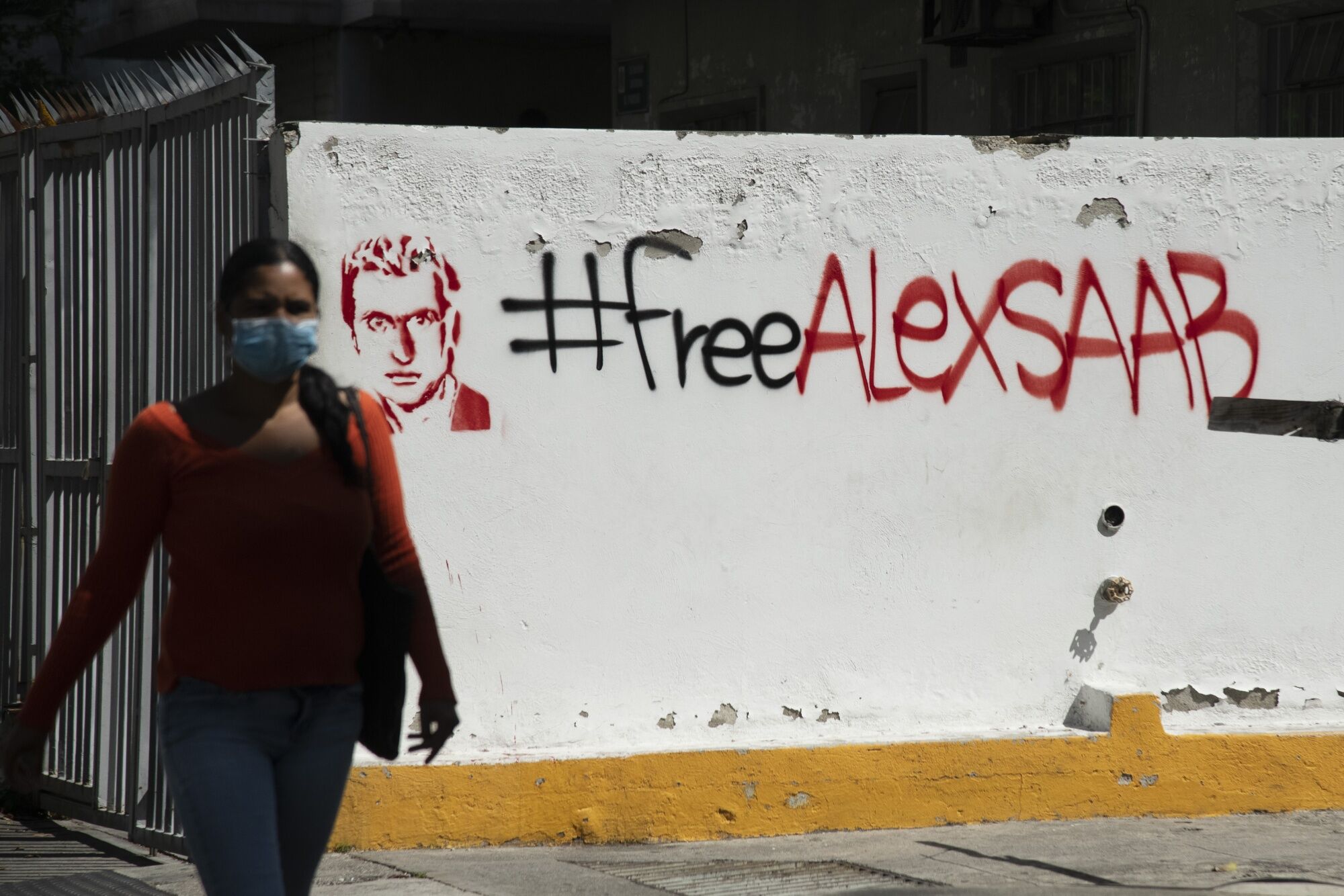 A pedestrian passes in front of “Free Alex Saab” graffiti " in Caracas, on Feb. 4.