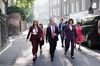 Labour leader Sir Keir Starmer walking down a sunny, back-lit street with fellow cabinet members walking with him — one at each side and five following behind