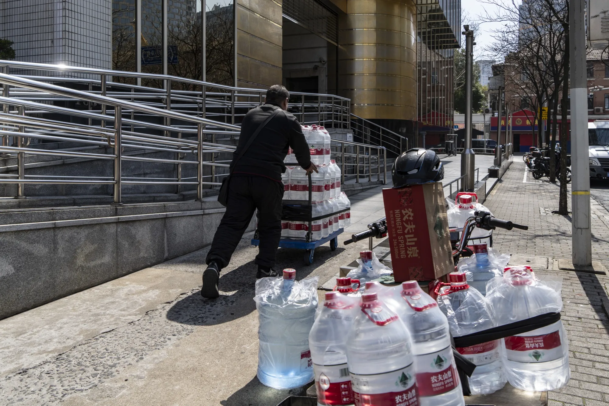 A delivery worker pushes a cart filled with bottles of Nongfu Spring Co. water in Shanghai.
