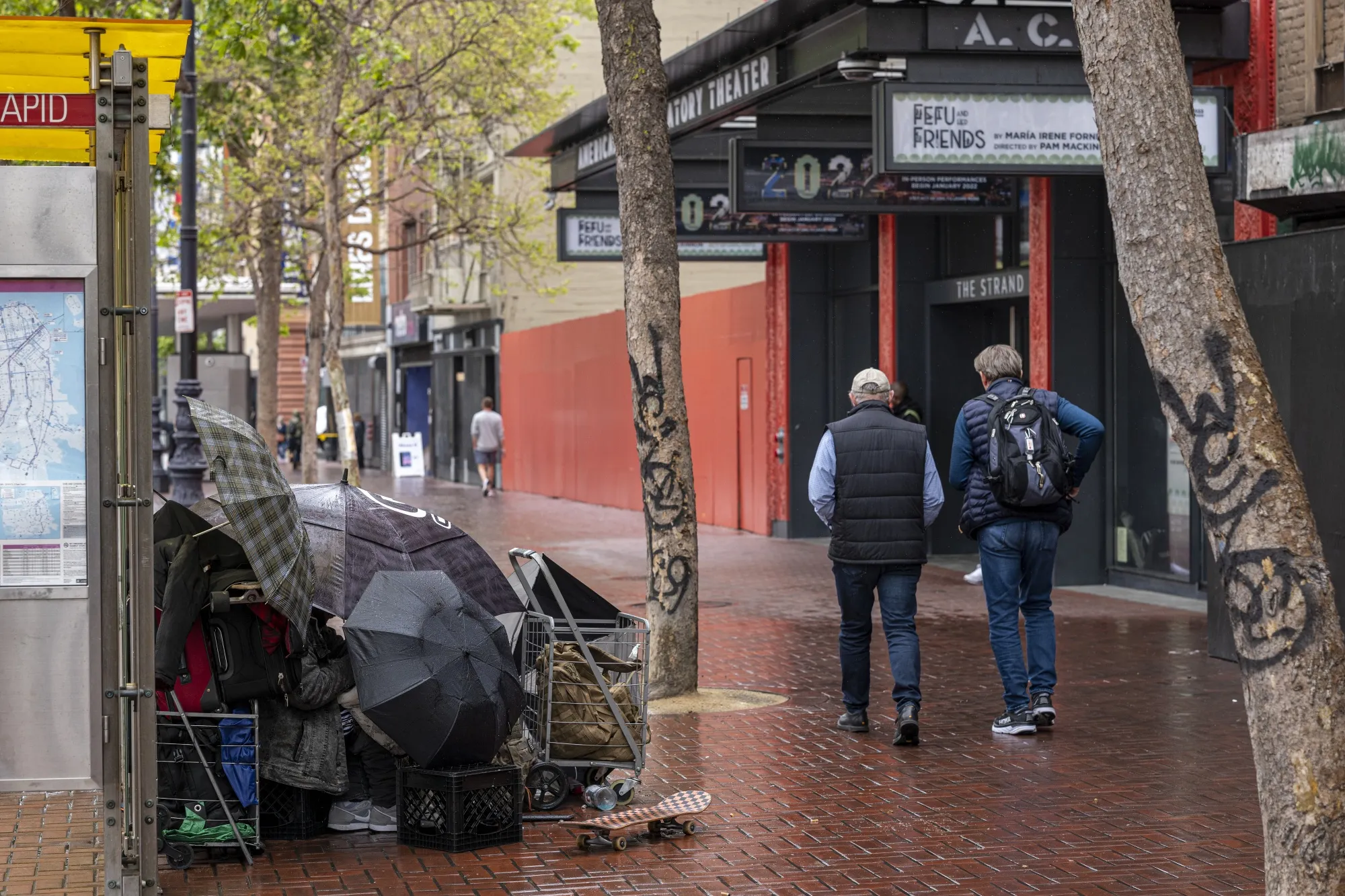 Pedestrians walk past a sidewalk&nbsp;shelter for a person experiencing homelessness on Market Street in downtown San Francisco in April 2022.