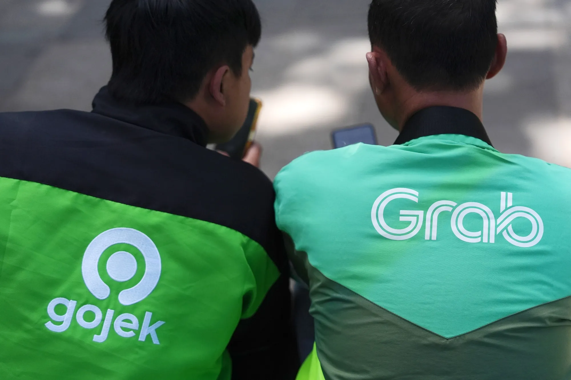 A Gojek and a Grab driver check their smartphones in Jakarta, Indonesia.