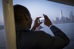 Isaac Osei-Acheampong photographs the New York City Skyline as he rides a ferry from Ellis Island after becoming a United States Citizen at a special U.S. naturalization ceremony.