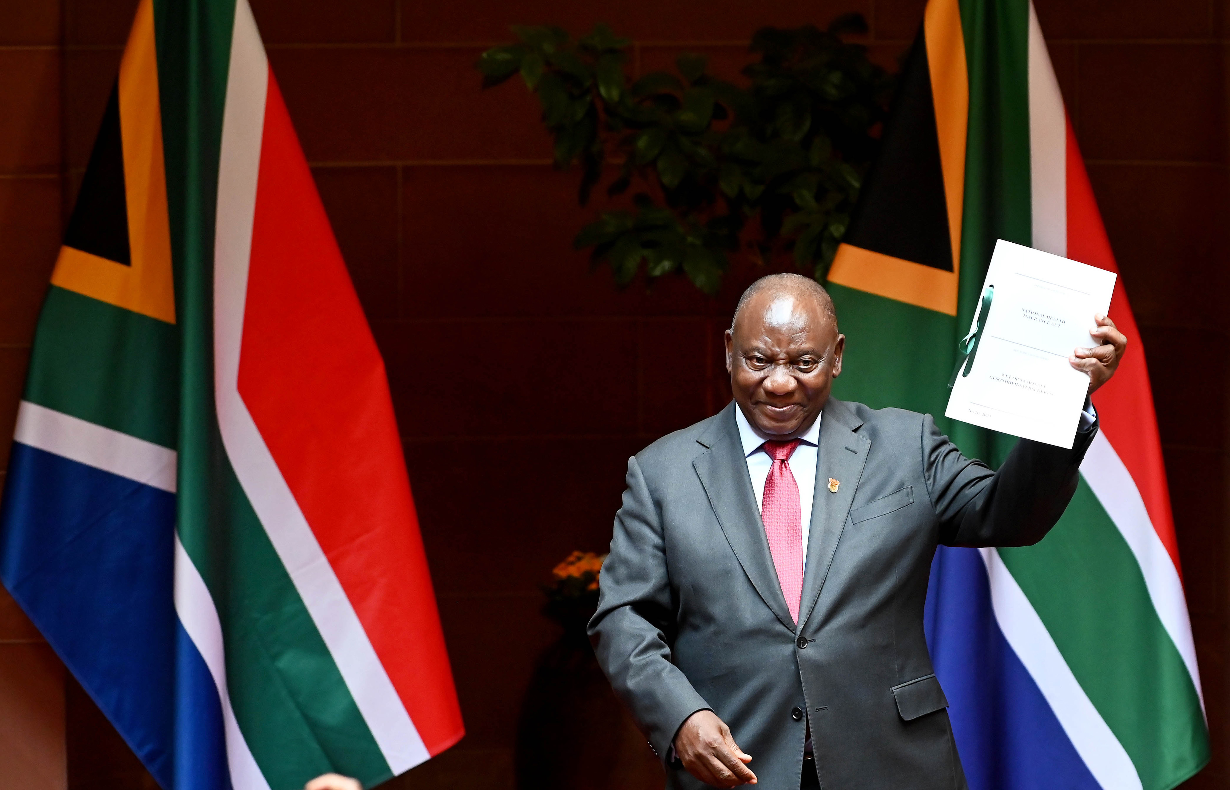 Cyril Ramaphosa shows the signed bill for National Health Insurance signed into law in Pretoria, South Africa on May 15.