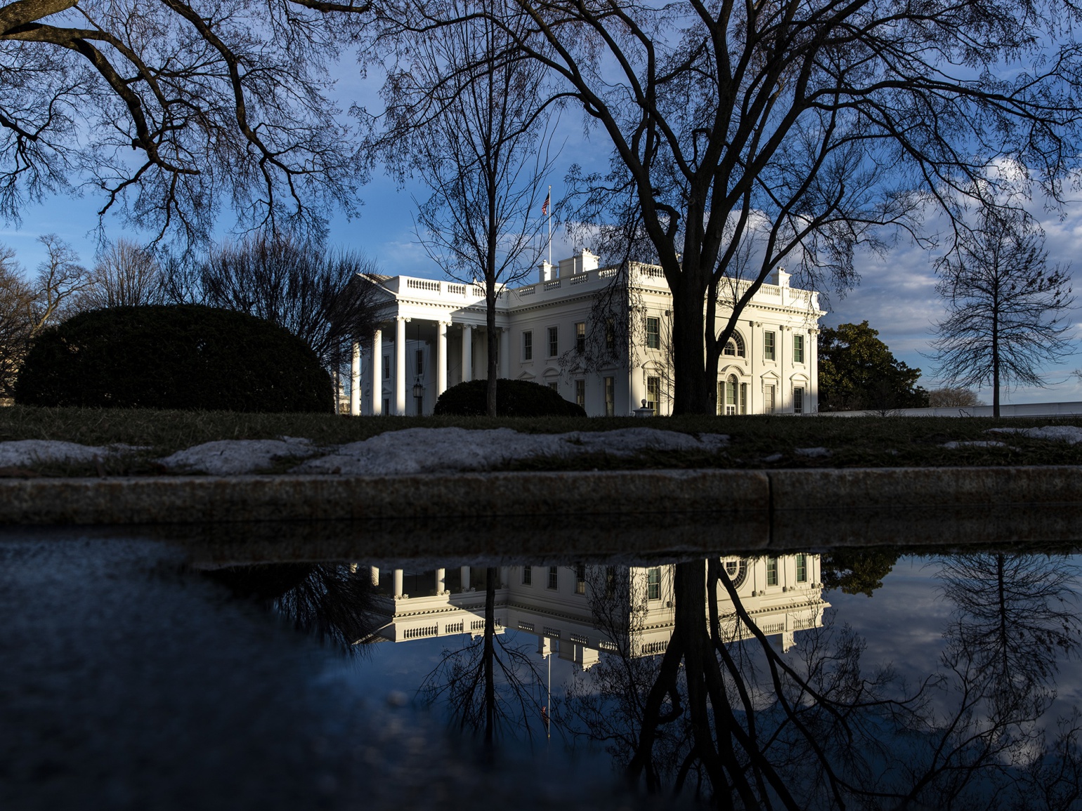 The White House is seen reflected in a puddle in Washington, D.C.