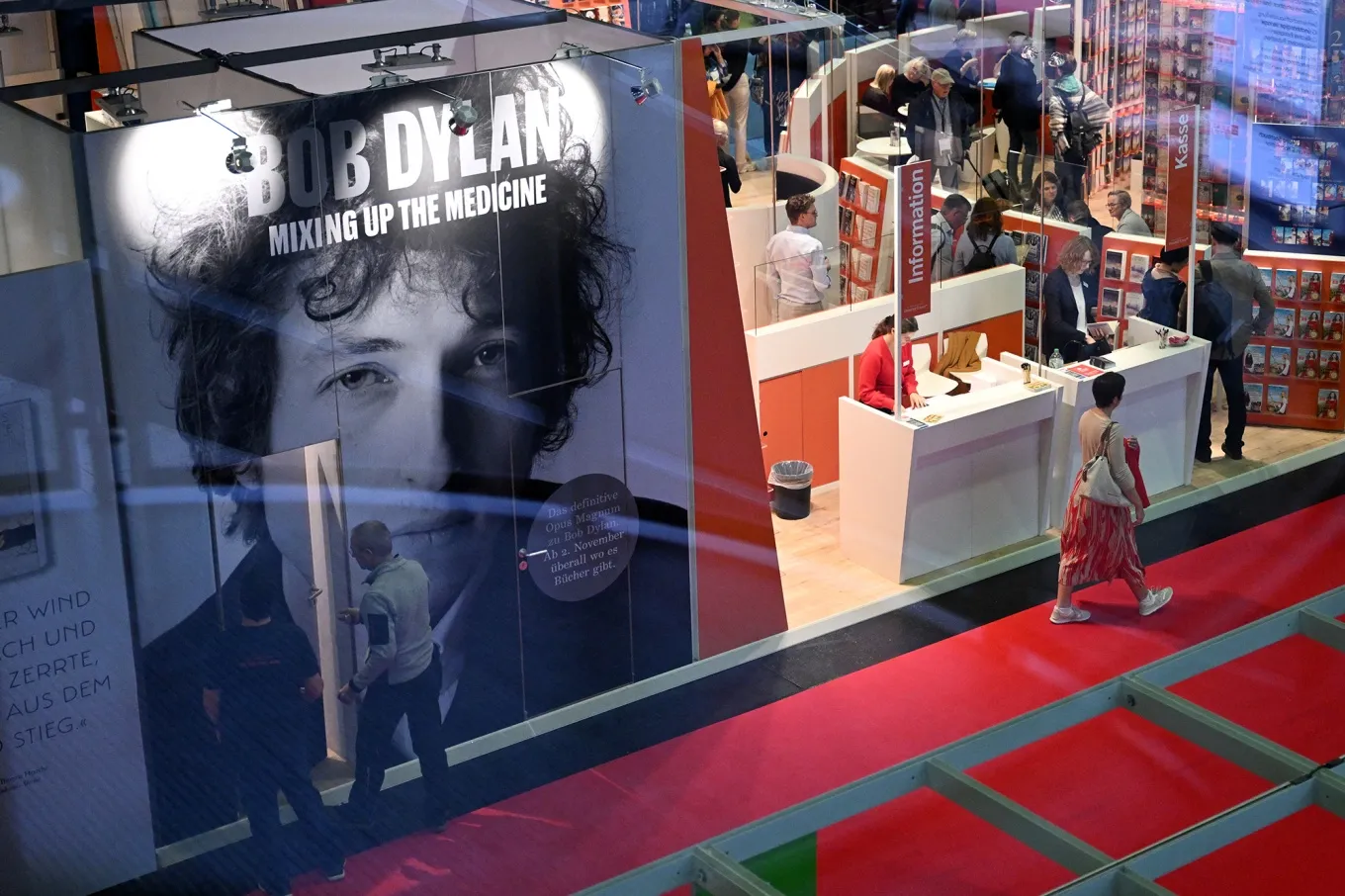 People walk past a booth promoting the book by Mark Davidson and Parker Fishel 'Bob Dylan: Mixing Up the Medicine’.