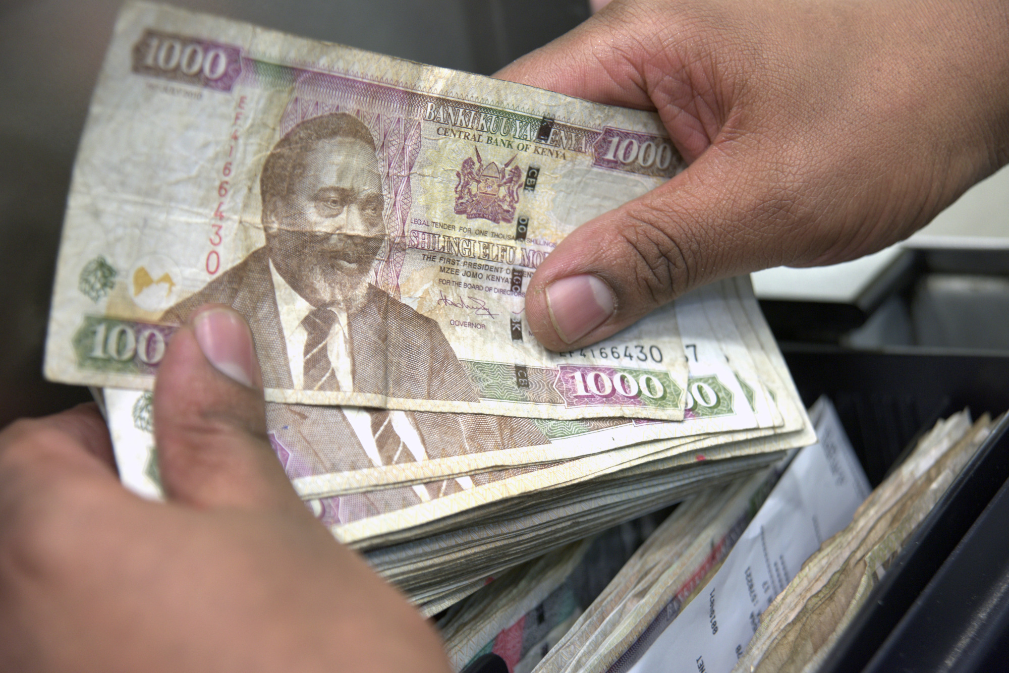 An employee holds Kenyan 1000 shilling currency notes at a cash desk inside a Nakumatt Holdings Ltd. supermarket in Nairobi, Kenya, on Saturday, Feb. 18, 2017. Nakumatt is Kenya's biggest supermarket chain.