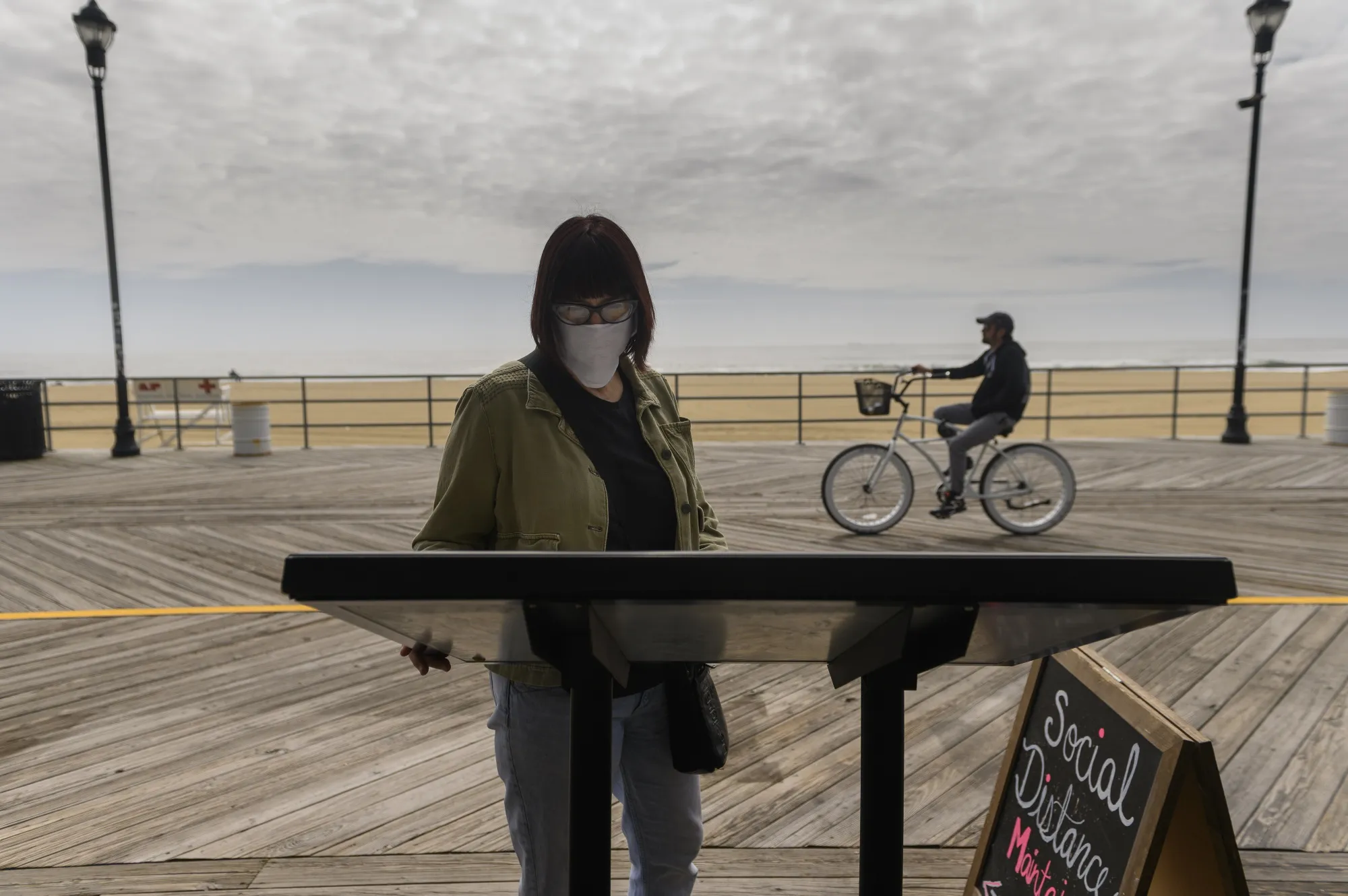 A person wearing a protective mask reads a takeout menu on the boardwalk in Asbury Park, New Jersey, on&nbsp;May 22.&nbsp;