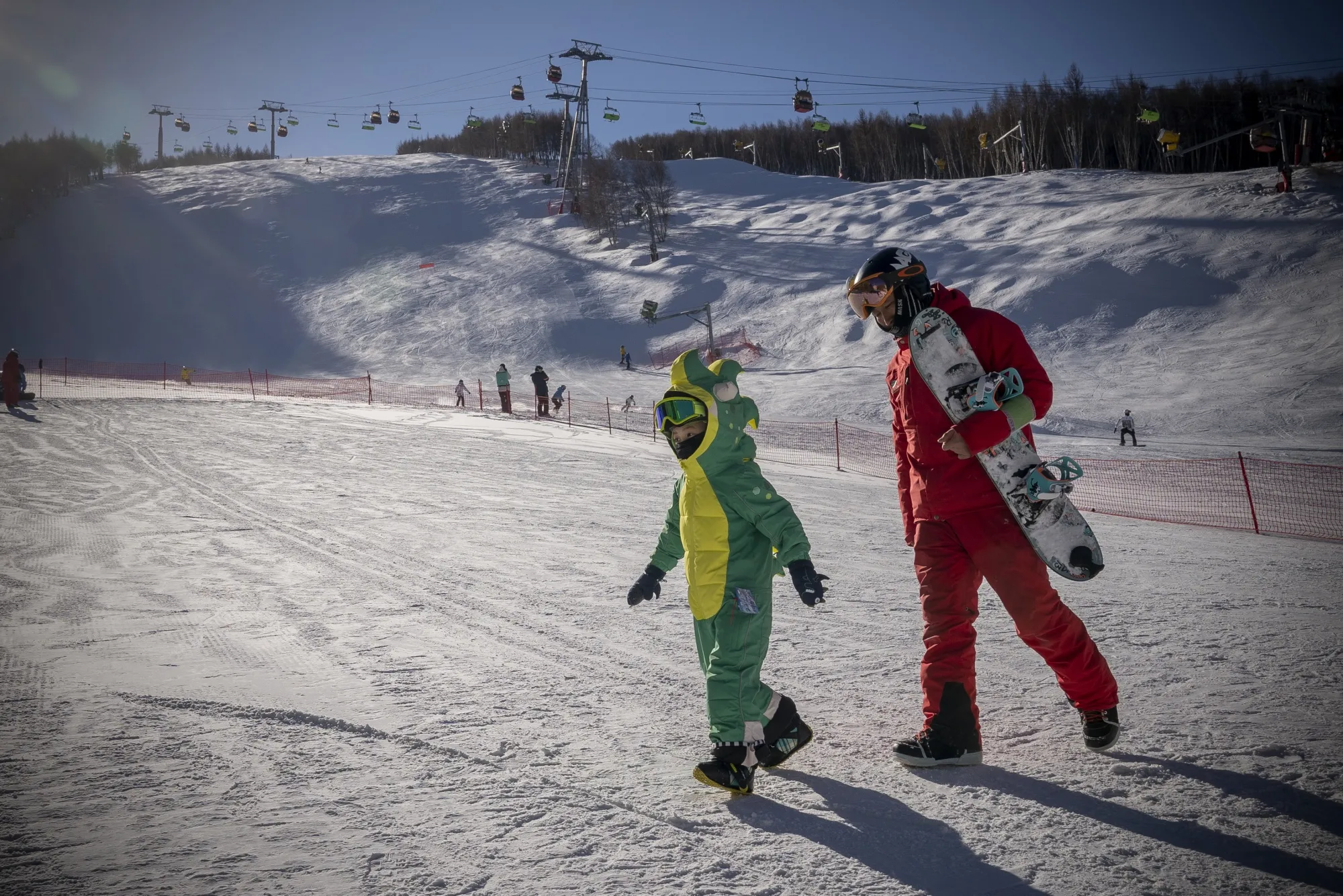 Snowboarders walk on artificial snow at Wanlong Ski Resort in the Chongli district of Zhangjiakou, which is helping to host the&nbsp;Beijing Winter Olympics.