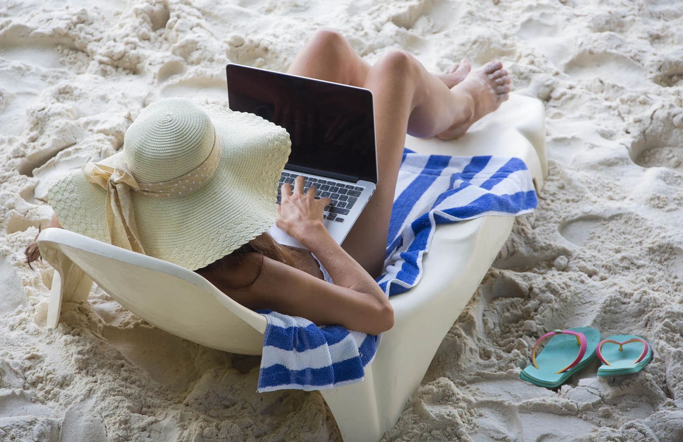A woman uses a laptop at Patata beach in Seychelles.
