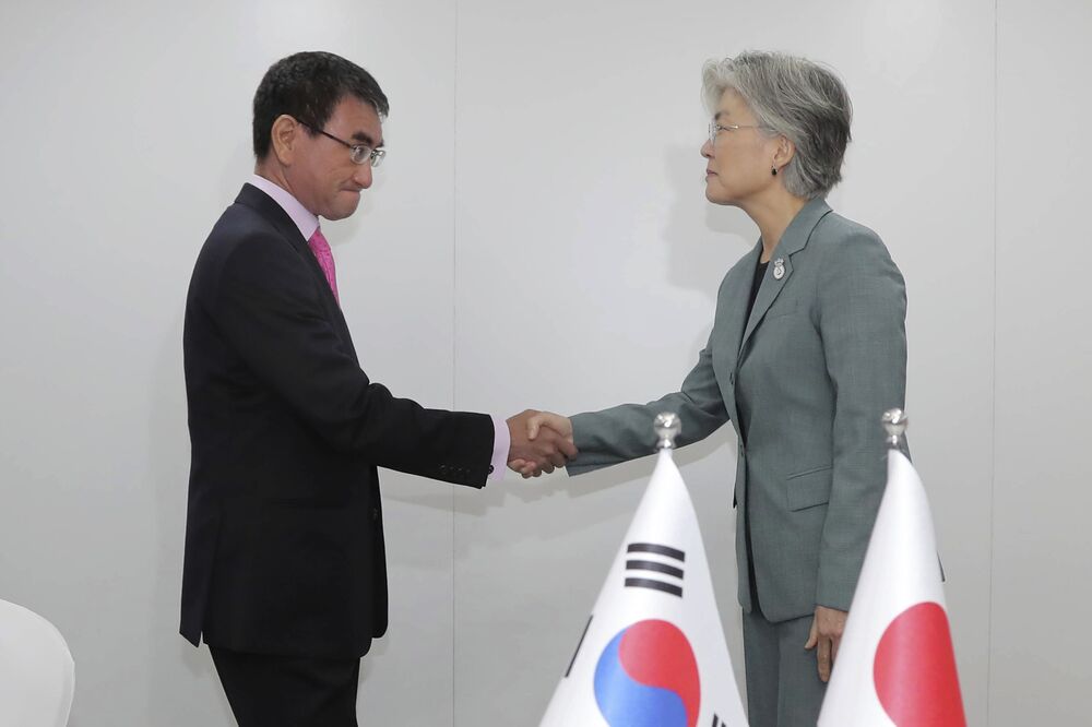 Taro Kono, left, shakes hands with Kang Kyung-wha in Bangkok.