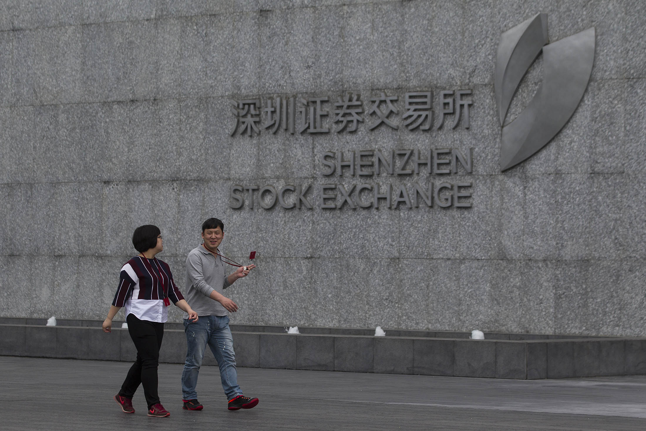 People walk past Shenzhen Stock Exchange building
