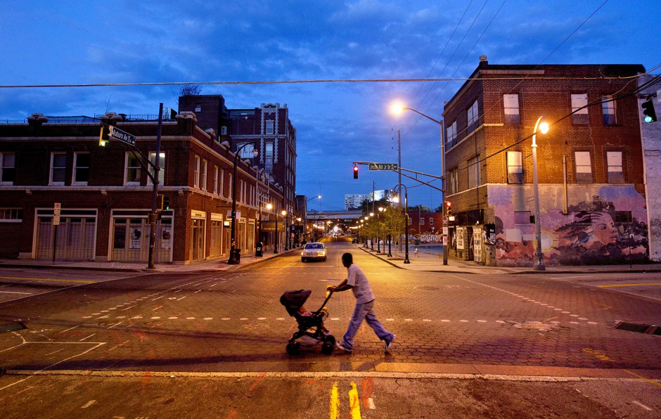 A man pushes a stroller through a crosswalk after dusk in Atlanta, Georgia.