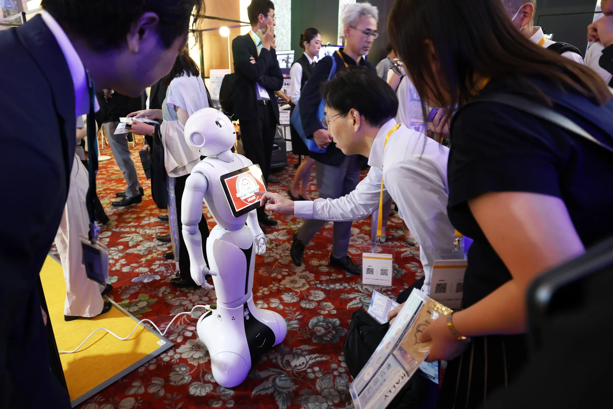 Attendees interact with a SoftBank Group Corp. Pepper humanoid robot at the SoftBank World event in Tokyo, Japan, on Wednesday, July 16, 2025. SoftBank World is the group's annual event for customers and suppliers.