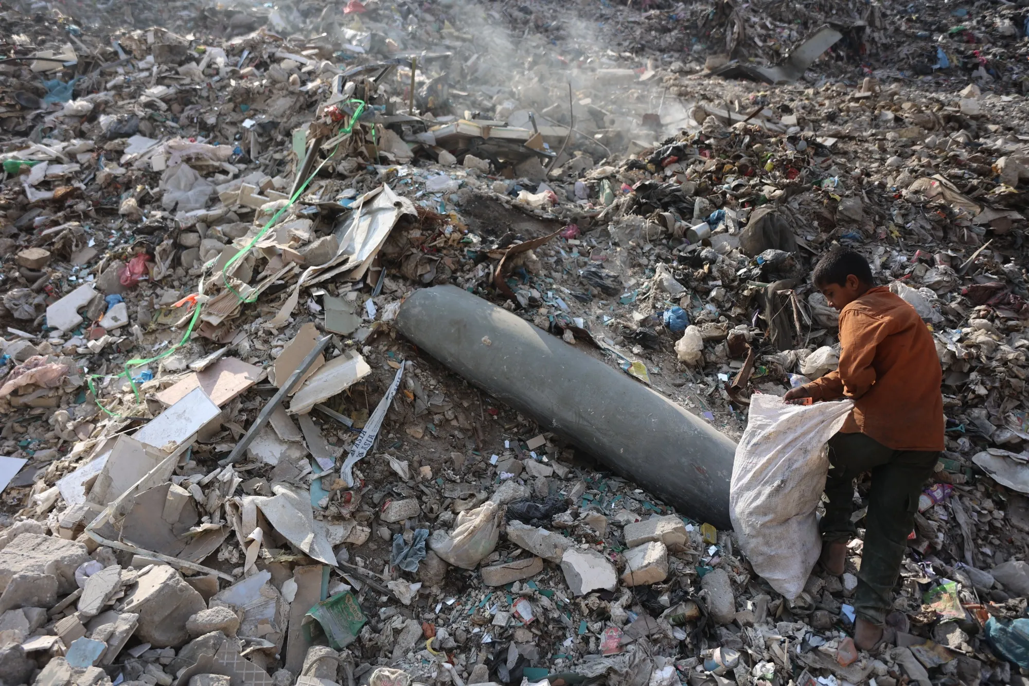 A Palestinian boy collects plastic near an unexploded missile at a rubbish dump in the Firas market area of Gaza City on Nov. 12.