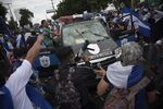 People attack a police car in Managua on Sept. 2.