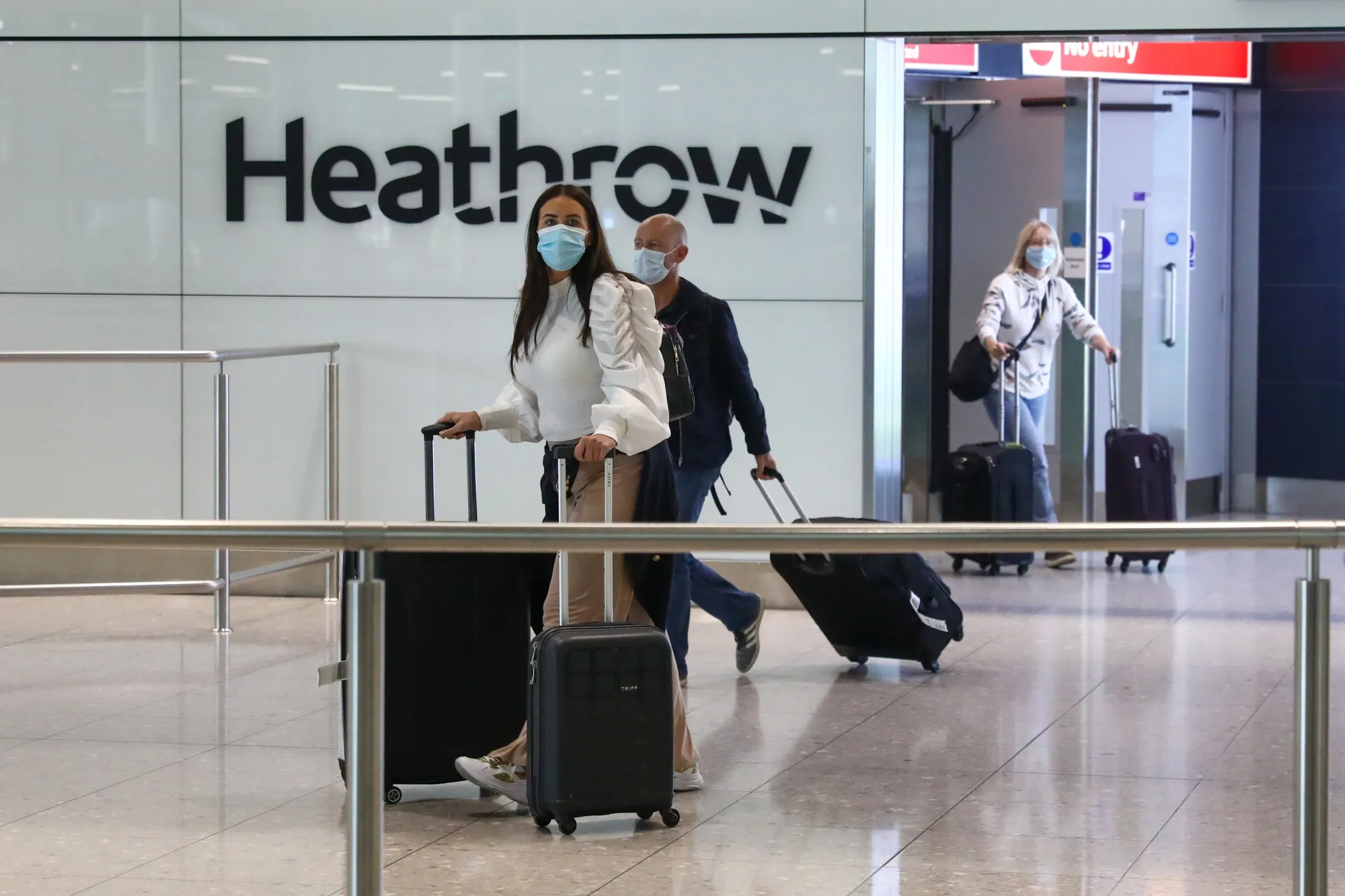 Passengers, wearing protective face masks, walk through the international arrivals hall&nbsp;at London Heathrow Airport.