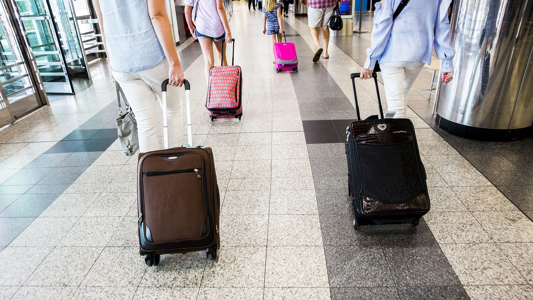 Travelers pull luggage while walking through LaGuardia Airport in New York on June 29, 2017.
