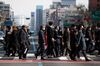 Pedestrians wearing protective masks cross a road in Seoul, South Korea, on Monday, Feb. 24, 2020.