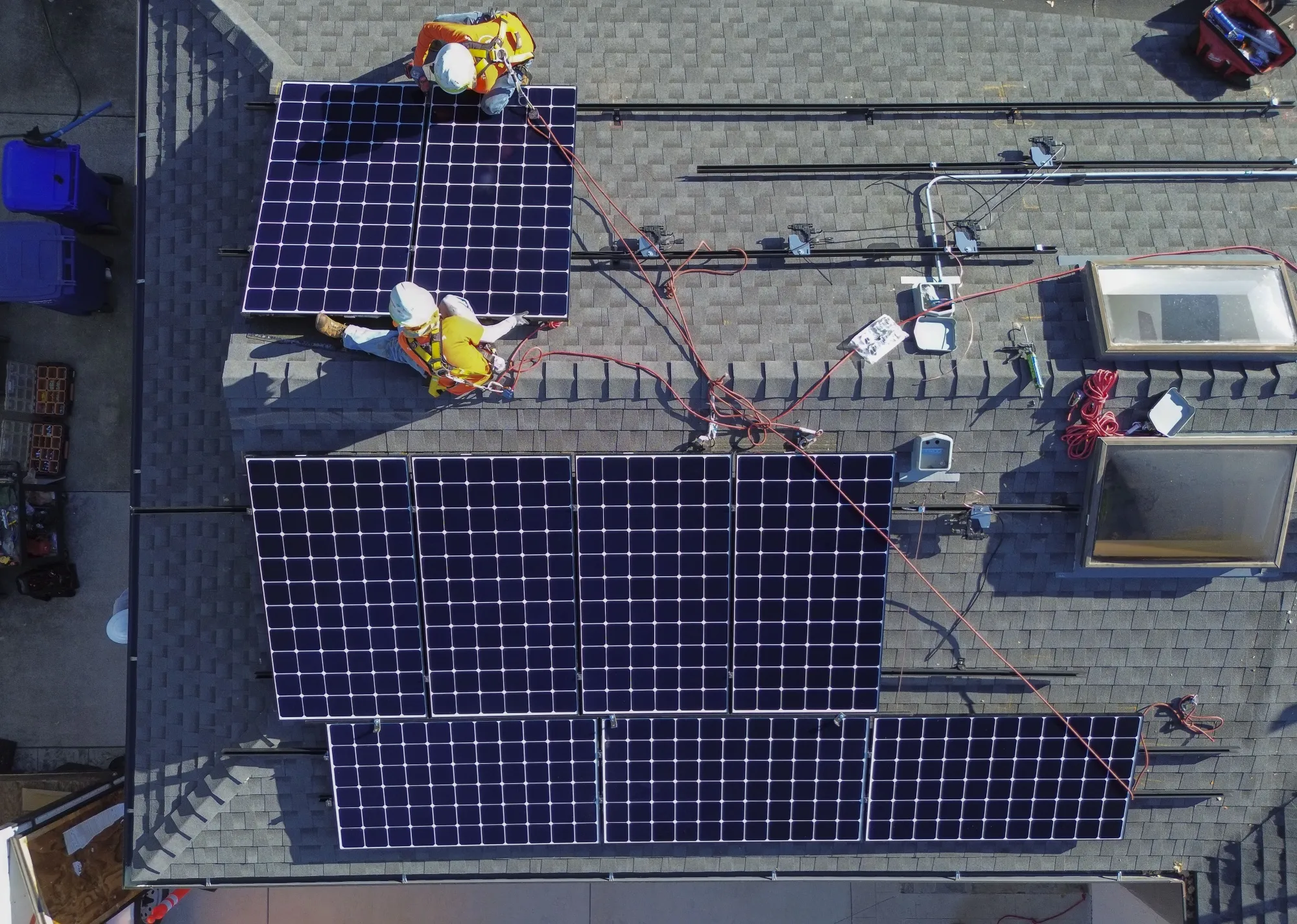 Workers install solar panels on the rooftop of a home in California.