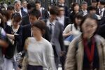 Morning commuters cross a road in Tokyo, Japan, on Tuesday, May 7, 2019.