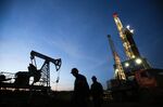 Oil workers pass a pumping unit at a drilling site operated by near Almetyevsk, Russia.