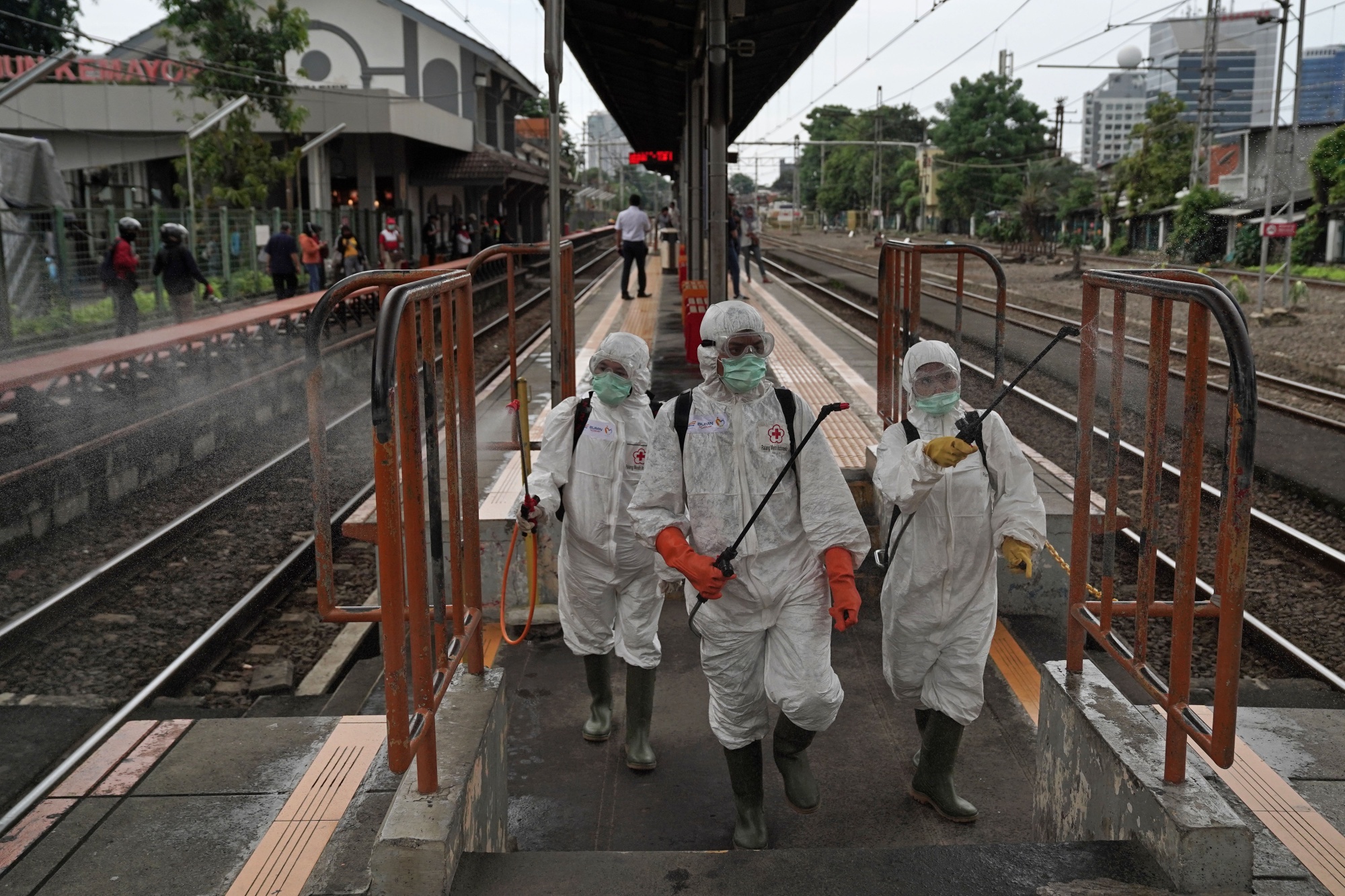 Members of the Indonesian Red Cross Society (IFRC) wearing protective suits and masks spray disinfectants on railings on a platform at the Kemayoran train station in Jakarta.