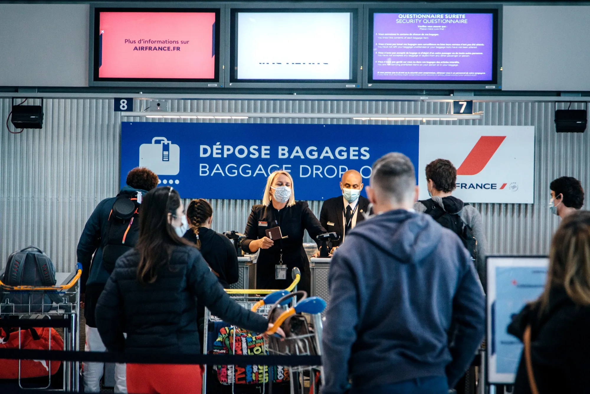 Employees wearing protective face masks serve travelers at the Air France-KLM baggage drop-off area at Charles de Gaulle Airport,&nbsp;in Roissy, France, on&nbsp;May 14.