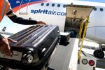 A ground crew member loads baggage onto a Spirit Airlines plane at the San Diego International Airport