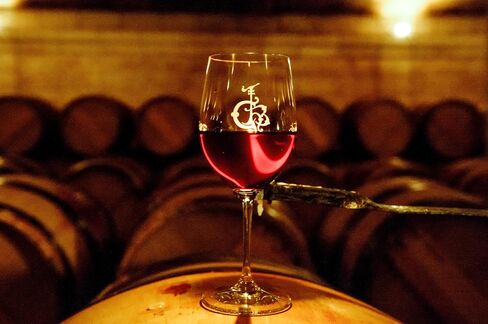 A glass of red wine stands on an oak barrel in the cellar of Château Haut-Brion in Pessac-Léognan.
